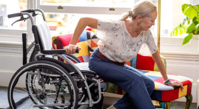 An-elder-flipped-up-the-armrest-of-a-wheelchair-and-transferring-herself-to-a-coach