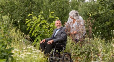 An-elder-sitting-in-a-wheelchair-accompanied-by-his-partner