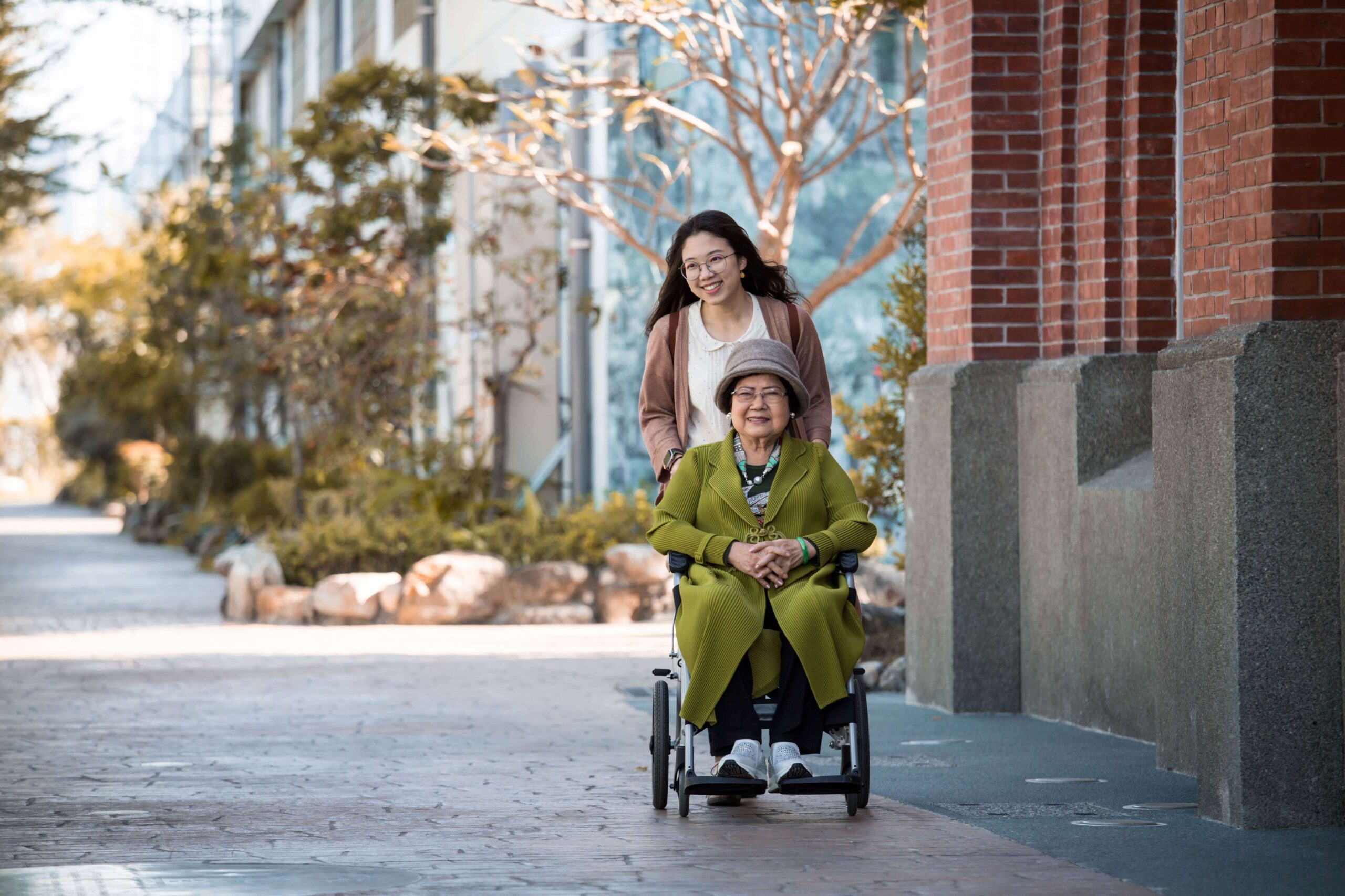 An-elderly-woman-in-a-wheelchair-propelled-by-her-granddaughter