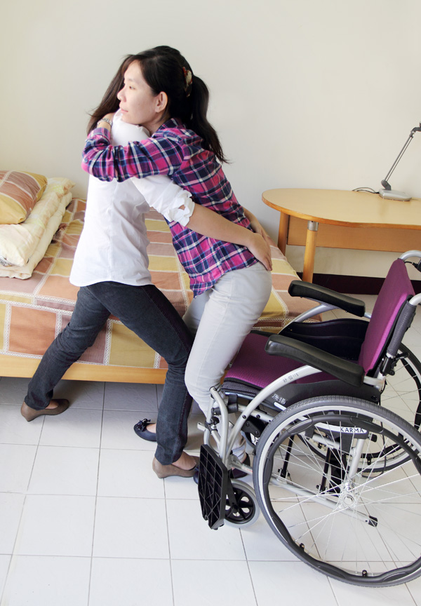 A-caregiver-is-transfering-a-patient-from-the-bed-to-the-wheelchair