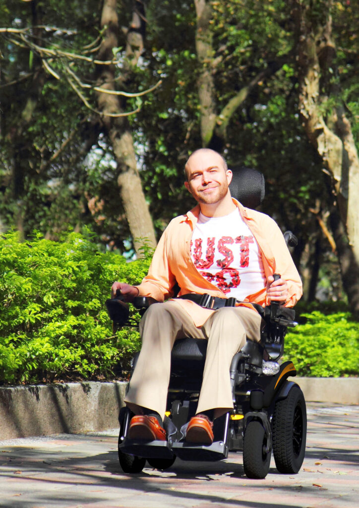 Man-in-a-power-wheelchair-smiling-happily-under-the-sunlight